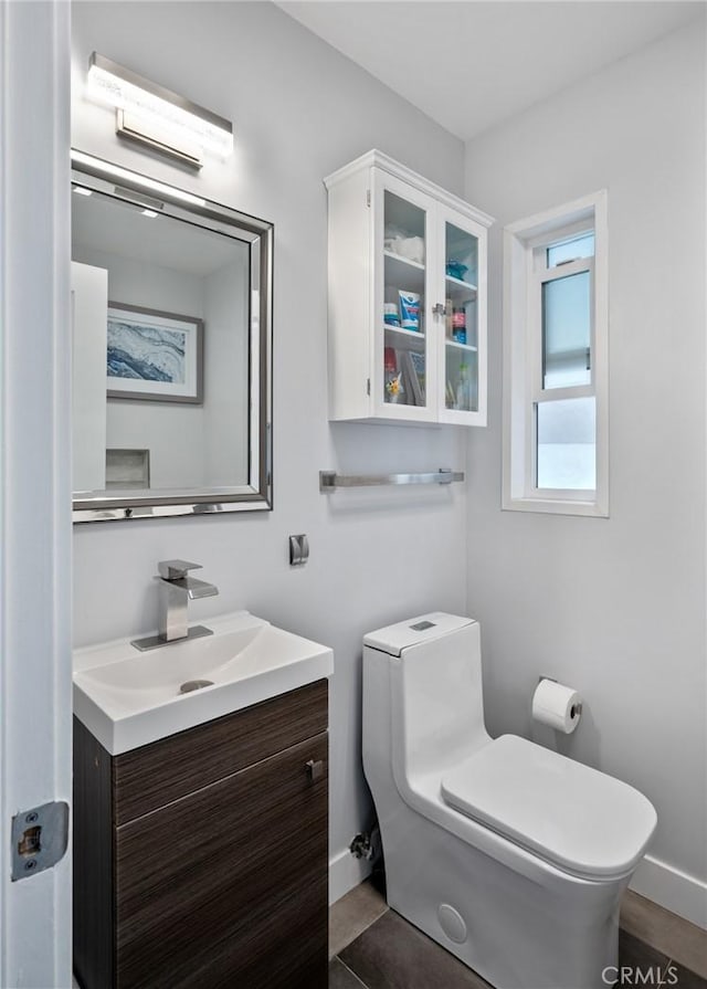 bathroom with toilet, baseboards, and vanity