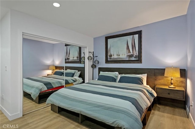 bedroom with a closet, wood finished floors, baseboards, and recessed lighting