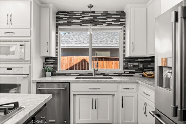 kitchen with a sink, stainless steel appliances, backsplash, and white cabinetry