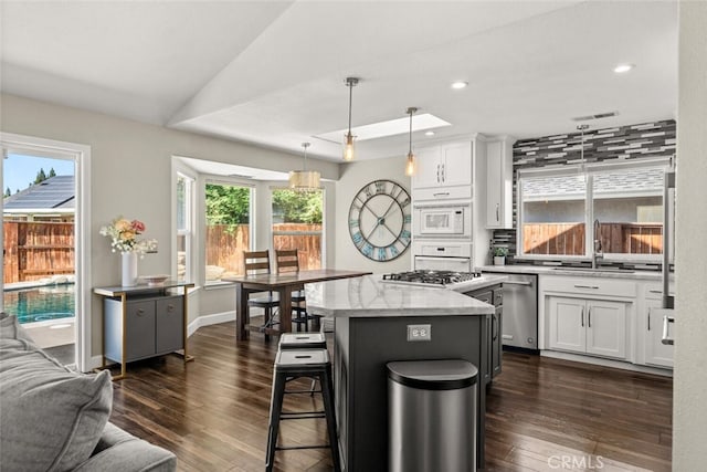 kitchen featuring white cabinets, appliances with stainless steel finishes, a center island, and dark wood-type flooring