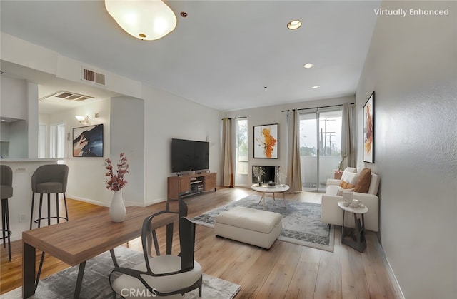 living area featuring baseboards, visible vents, and wood finished floors