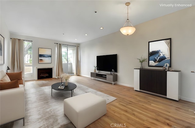living area featuring a fireplace, light wood-style flooring, baseboards, and recessed lighting
