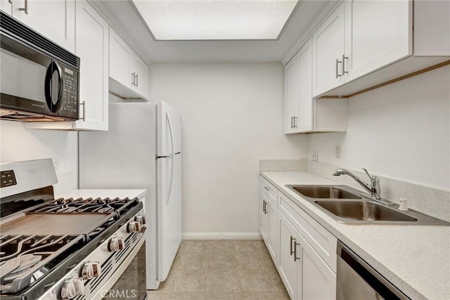 kitchen featuring white cabinetry, appliances with stainless steel finishes, baseboards, and a sink