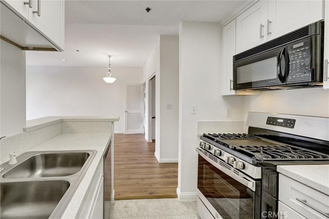 kitchen with a sink, white cabinets, light wood-type flooring, light countertops, and appliances with stainless steel finishes