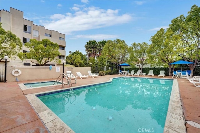 pool with a patio area, fence, and a community hot tub
