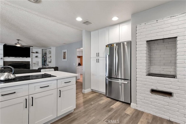kitchen featuring freestanding refrigerator, a fireplace, white cabinetry, visible vents, and light wood-type flooring