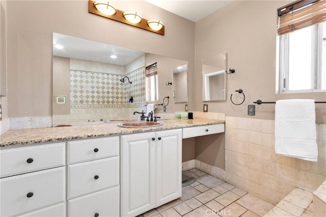 bathroom with tile walls, vanity, wainscoting, and tiled shower