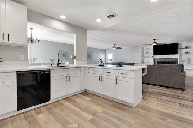 kitchen featuring a sink, a peninsula, ceiling fan with notable chandelier, dishwasher, and open floor plan