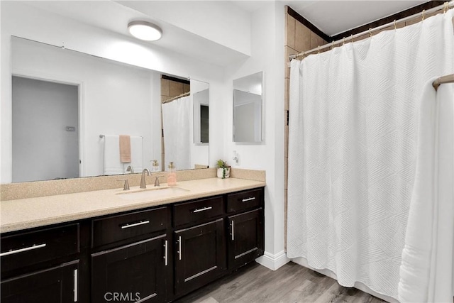 full bath with a shower with curtain, vanity, and wood finished floors