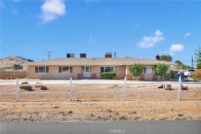 ranch-style house with stucco siding, a chimney, and fence