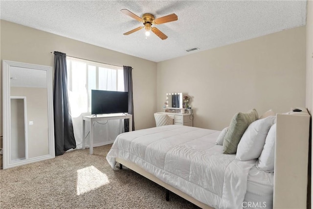 carpeted bedroom featuring ceiling fan, visible vents, and a textured ceiling
