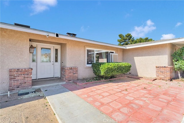 property entrance with a patio, stucco siding, and brick siding