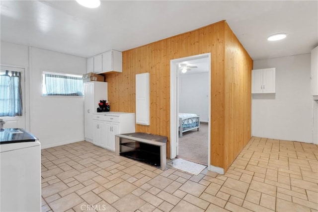 kitchen featuring wooden walls, white cabinetry, brick patterned floor, and washer / dryer