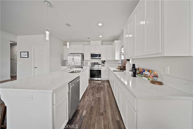 kitchen with a sink, stainless steel appliances, white cabinets, dark wood-type flooring, and decorative light fixtures