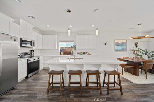 kitchen featuring light countertops, visible vents, appliances with stainless steel finishes, and a kitchen bar