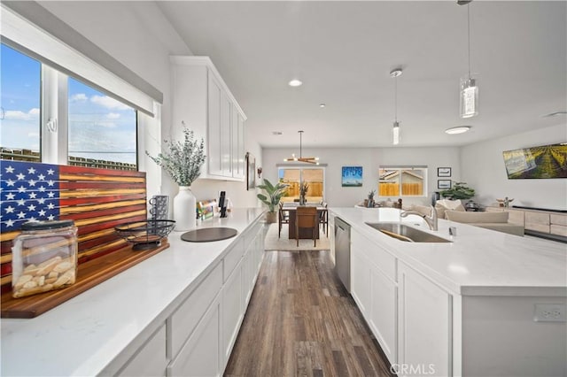kitchen with a sink, open floor plan, white cabinetry, stainless steel dishwasher, and dark wood-style floors