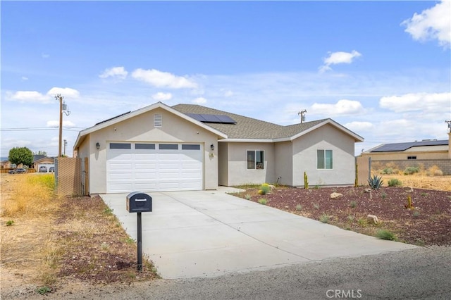 ranch-style home with fence, driveway, a garage, stucco siding, and solar panels