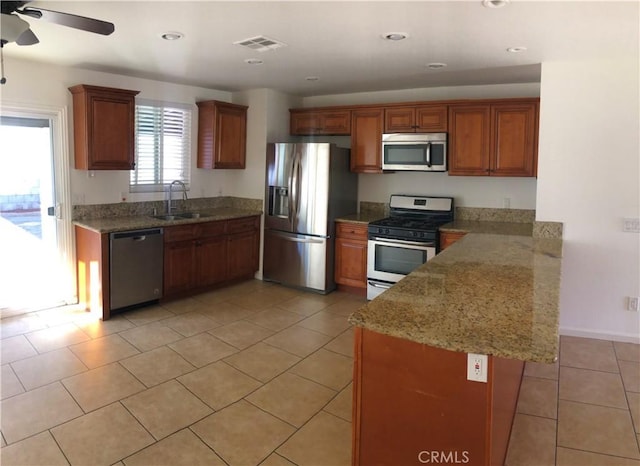 52415 Avenida Vallejo Ln, Quinta, CA 92253 - kitchen featuring appliances with stainless steel finishes, a sink, a peninsula, ceiling fan, and brown cabinetry