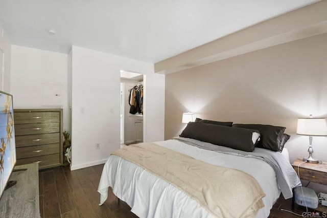 bedroom featuring a closet, baseboards, dark wood-style flooring, and a walk in closet
