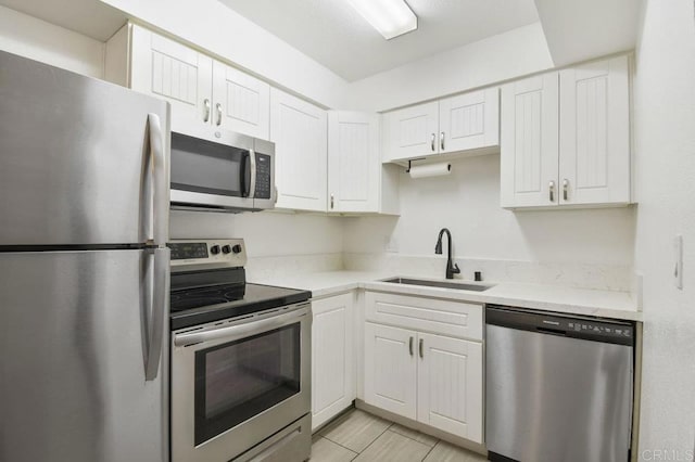 kitchen featuring a sink, stainless steel appliances, light stone countertops, and white cabinets