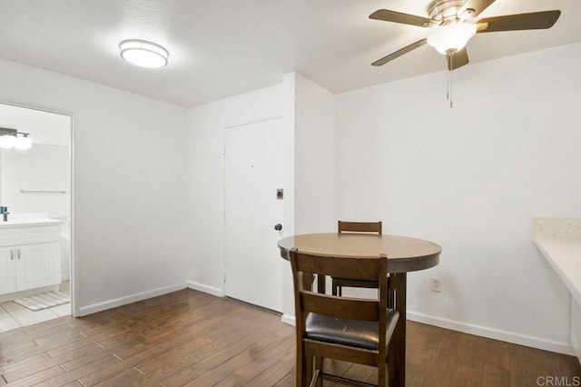 dining space featuring a ceiling fan, baseboards, and wood finished floors