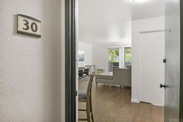 hallway with a textured wall and wood finished floors