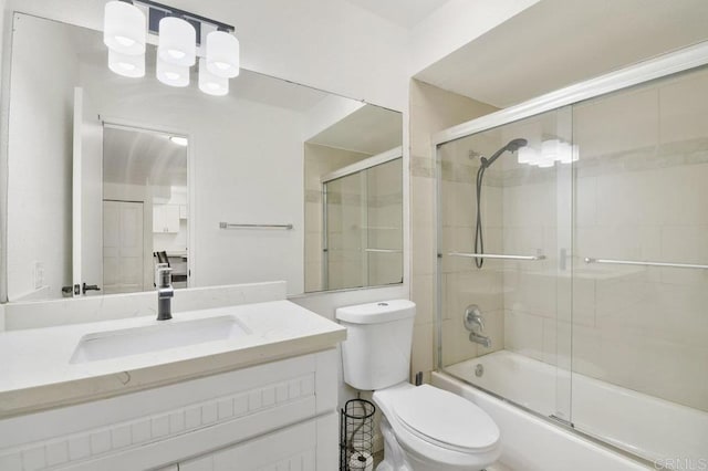 bathroom featuring toilet, bath / shower combo with glass door, and vanity
