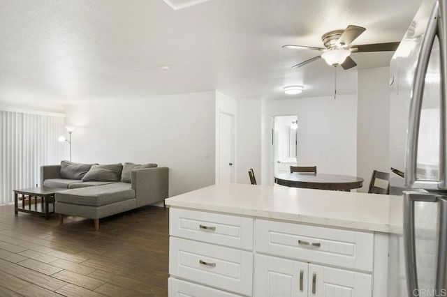 kitchen with freestanding refrigerator, dark wood-style flooring, white cabinetry, light countertops, and a ceiling fan