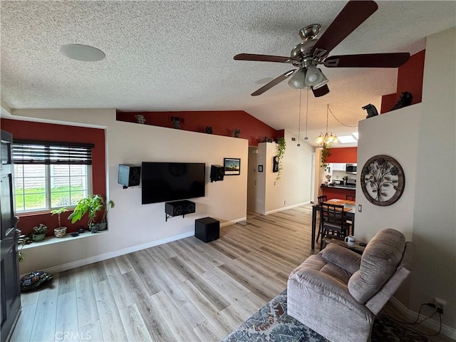 living area featuring wood finished floors, a textured ceiling, baseboards, ceiling fan, and vaulted ceiling