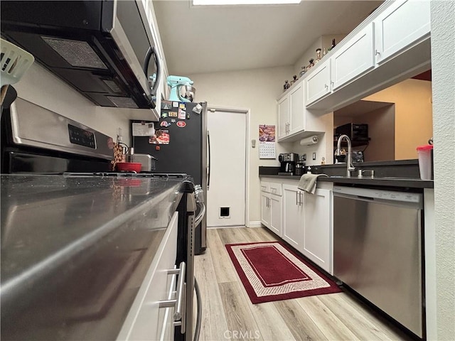 kitchen with a sink, light wood finished floors, white cabinetry, and appliances with stainless steel finishes