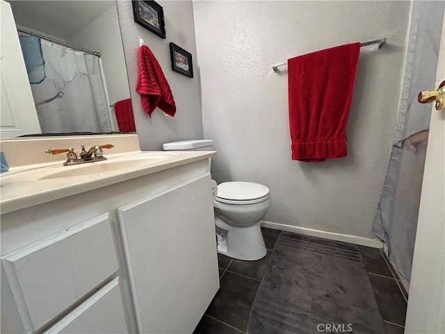 bathroom featuring toilet, baseboards, tile patterned floors, and vanity