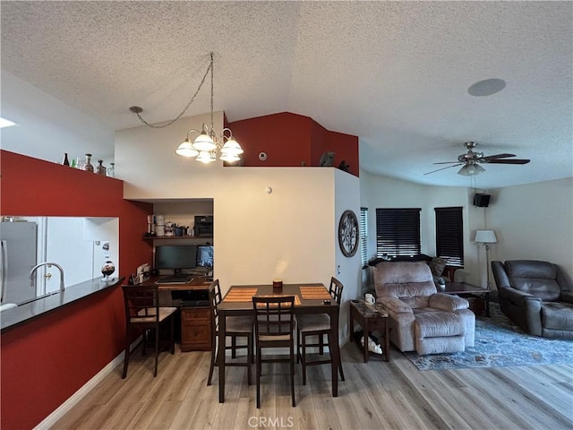 dining space featuring light wood-style flooring, ceiling fan with notable chandelier, a textured ceiling, and vaulted ceiling