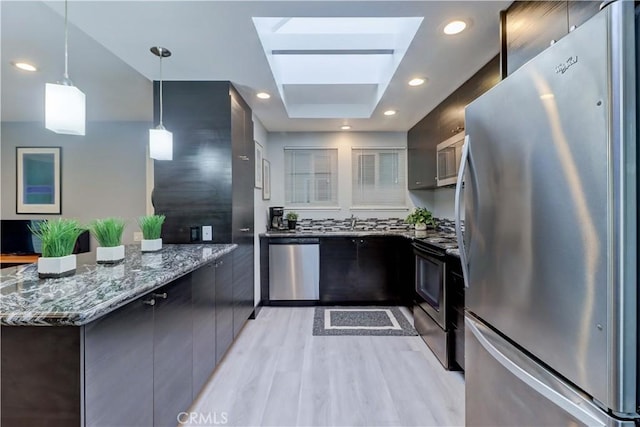774 Via Los Altos Unit P, Laguna Woods, CA 92637 - kitchen with stainless steel appliances, a peninsula, light wood-type flooring, dark stone counters, and a skylight