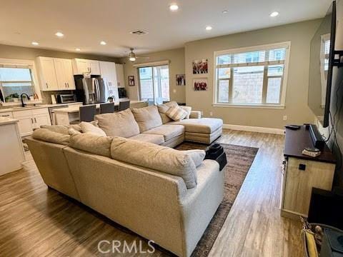 living room with light wood finished floors, baseboards, a ceiling fan, and recessed lighting