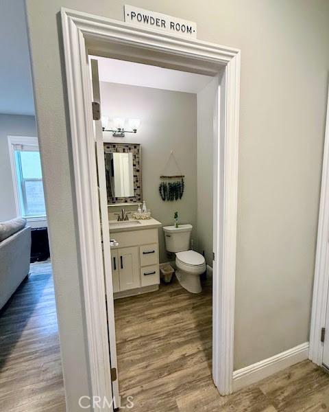 half bathroom featuring toilet, wood finished floors, and vanity