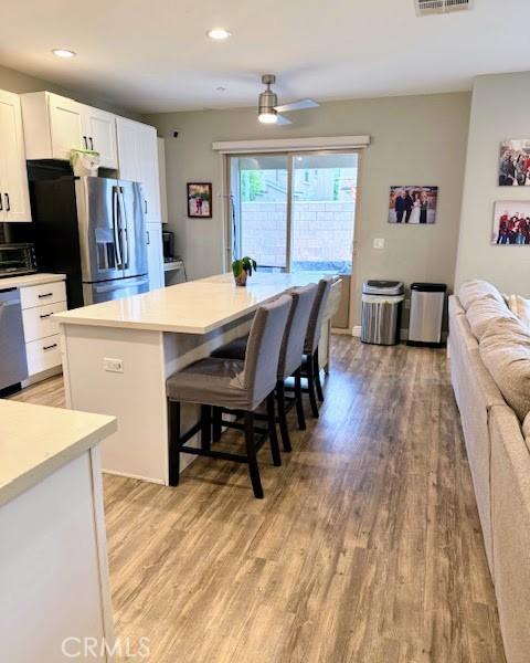 kitchen featuring white cabinetry, a kitchen island, light wood-type flooring, and appliances with stainless steel finishes