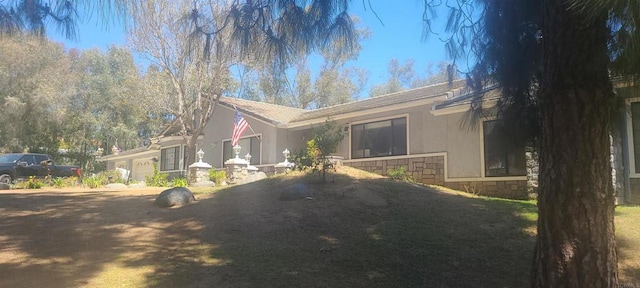 exterior space featuring stone siding, stucco siding, and a garage