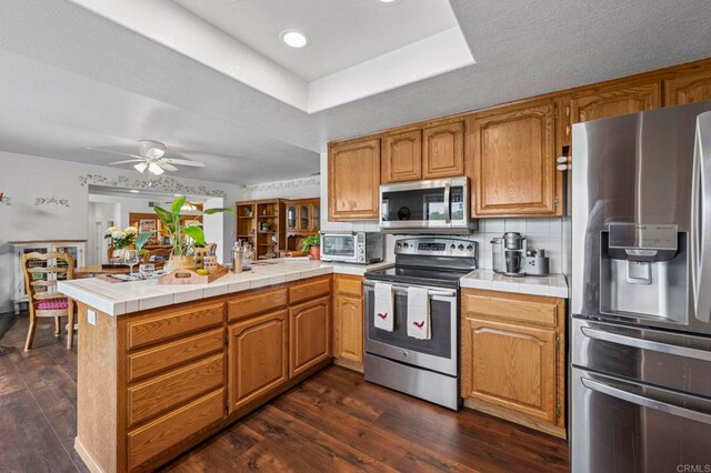 3048 Jason Rd, Fallbrook, CA 92028 - kitchen featuring appliances with stainless steel finishes, a peninsula, a raised ceiling, tile counters, and recessed lighting