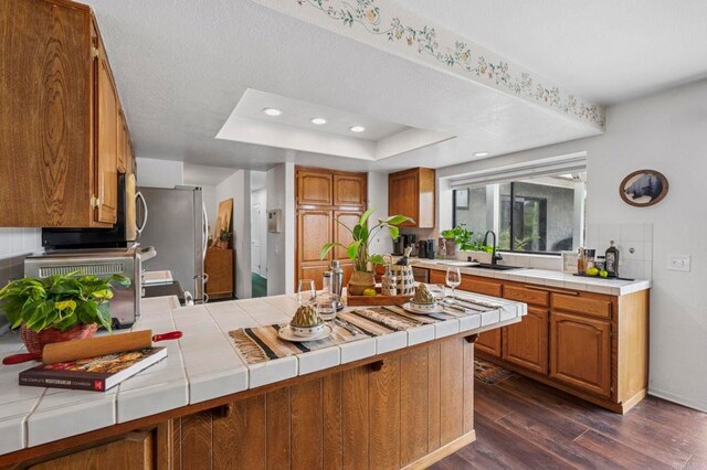 3048 Jason Rd, Fallbrook, CA 92028 - kitchen featuring a peninsula, tile countertops, dark wood-type flooring, appliances with stainless steel finishes, and brown cabinetry