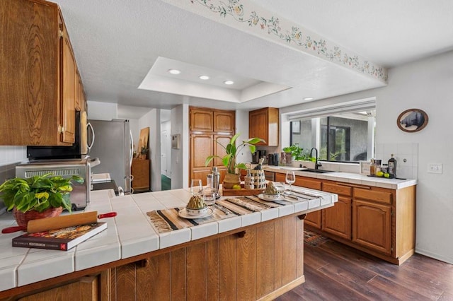3048 Jason Rd, Fallbrook, CA 92028 - kitchen featuring a peninsula, tile countertops, dark wood finished floors, brown cabinets, and freestanding refrigerator
