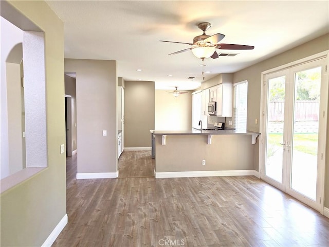 kitchen featuring a wealth of natural light, wood finished floors, stainless steel microwave, and a ceiling fan