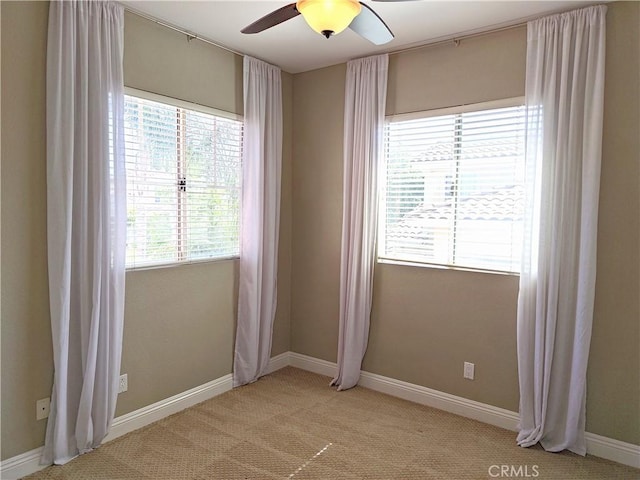 unfurnished room featuring baseboards, ceiling fan, and light colored carpet