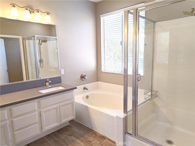 bathroom featuring a shower stall, a garden tub, vanity, and wood finished floors