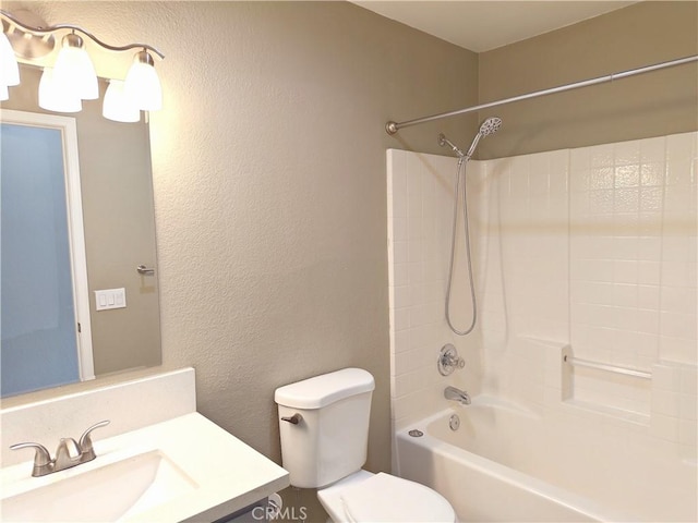 bathroom featuring toilet, shower / washtub combination, vanity, and a textured wall