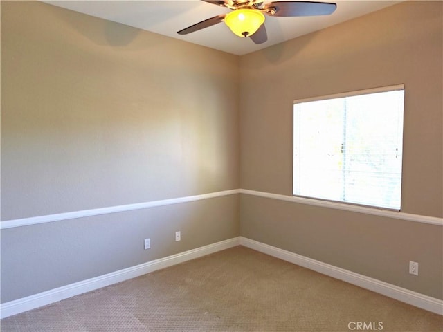 spare room featuring light carpet, baseboards, and a ceiling fan