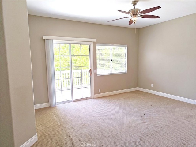 carpeted spare room with baseboards and a ceiling fan