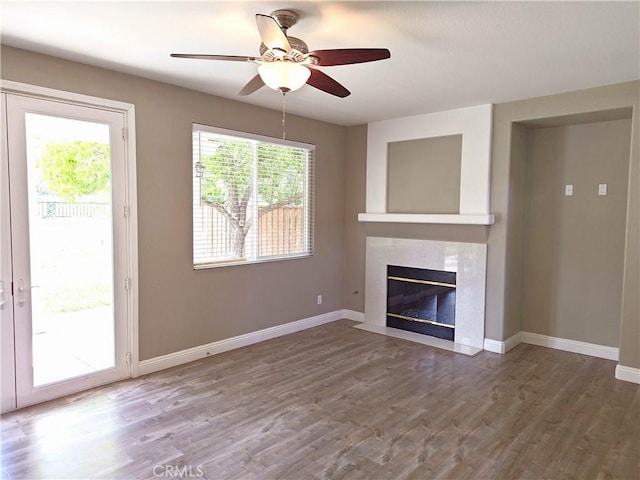 unfurnished living room featuring ceiling fan, wood finished floors, baseboards, and a fireplace with flush hearth