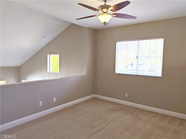 interior space featuring baseboards, lofted ceiling, ceiling fan, and light colored carpet