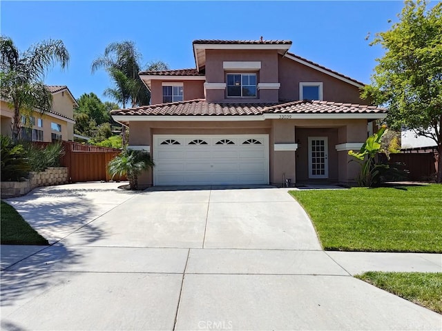 mediterranean / spanish-style house with driveway, stucco siding, a front yard, and fence