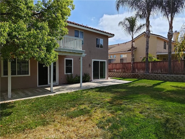 back of property with a balcony, a patio, stucco siding, and fence